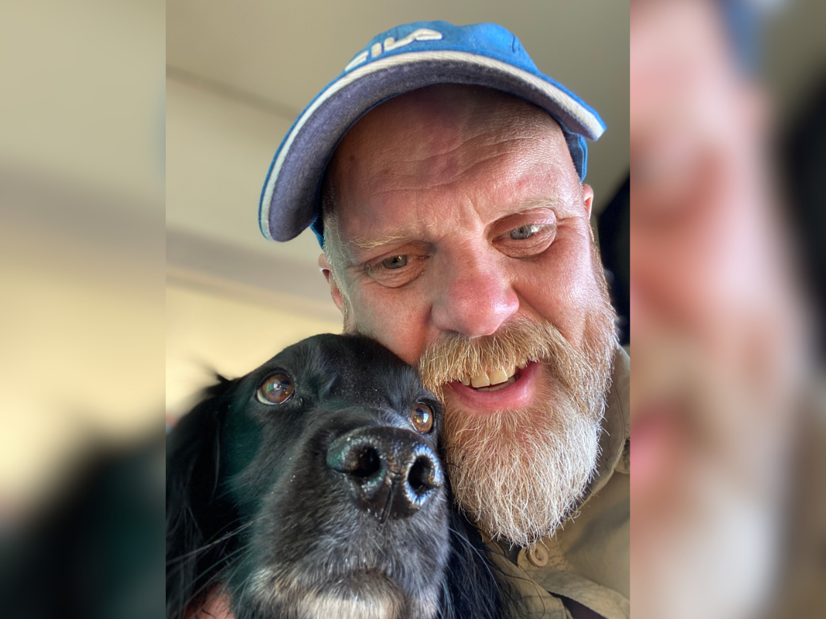 Richard with blue cap on with his black dog