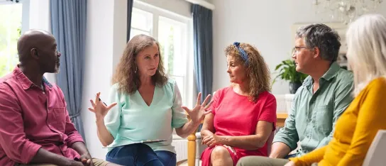 Support group of adults sitting in a circle having a discussion.