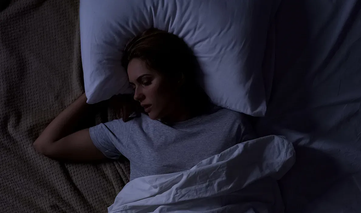 Woman lying in bed at night, appearing restless while trying to sleep.