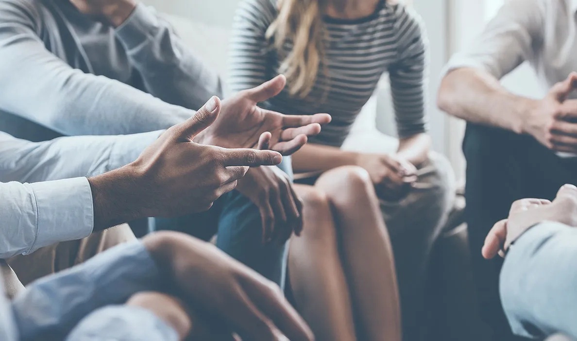 Close-up of hands and gestures of people engaged in a group conversation, suggesting active discussion.