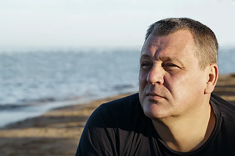 Middle aged white man sitting on the beach thoughtfully