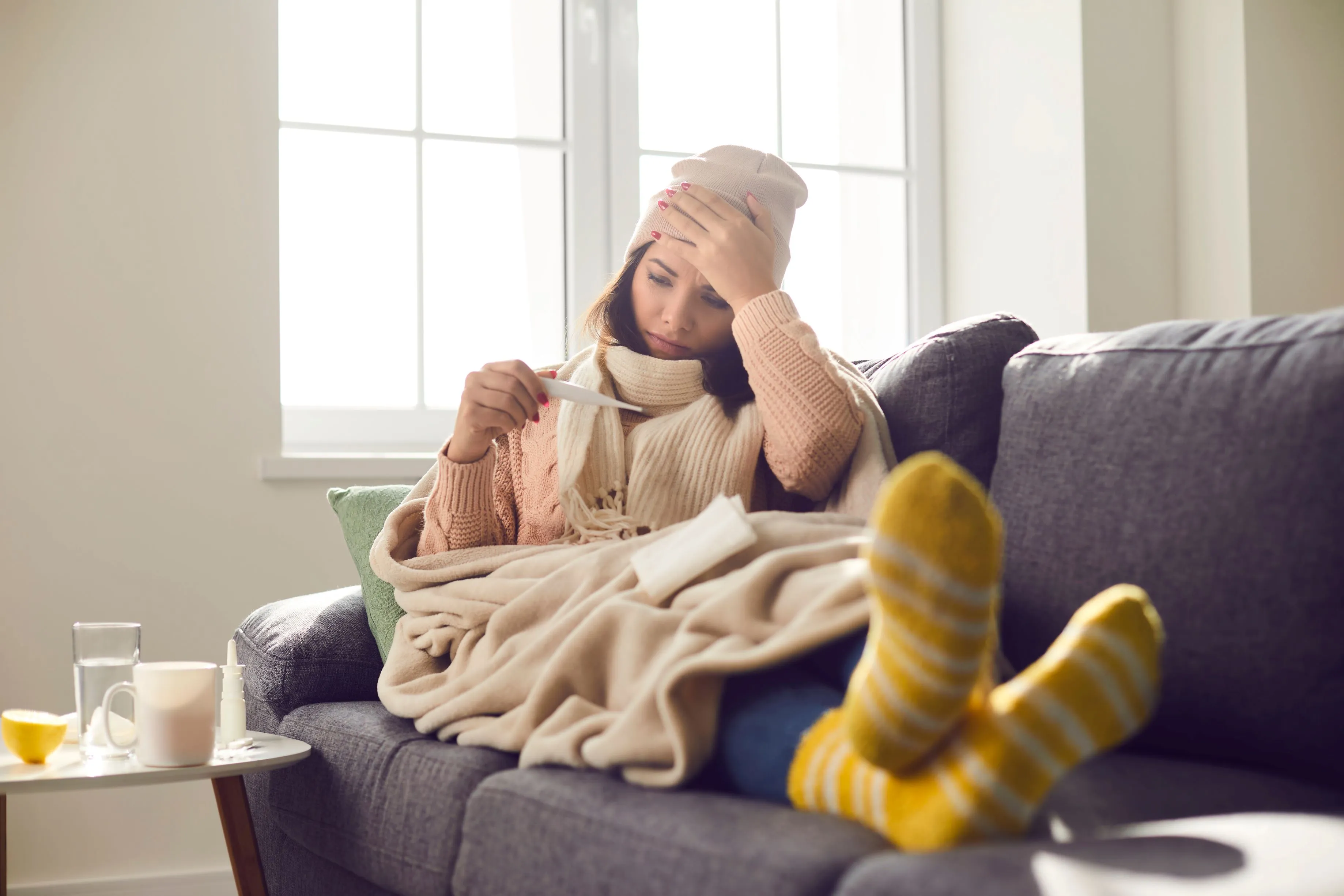 Woman sat on sofa looking at a thermometer