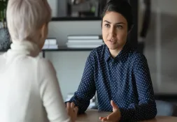Young woman engaged in a serious conversation with another person, emphasising active listening and compassionate communication.