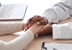 Close-up of a doctor compassionately holding a patient’s hand during a consultation.
