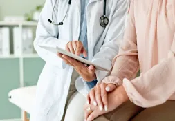 Doctor showing information on a digital tablet to a female patient in a medical office.