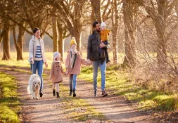 Family taking a break and enjoying a walk in a park on a sunny day.