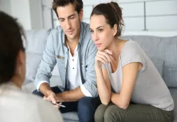 Young couple sitting on a couch, attentively listening and discussing with a professional.