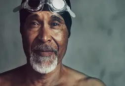 A confident older man wearing swimming goggles and a cap, showcasing an active and healthy lifestyle.