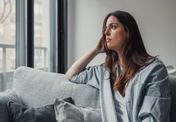 Woman sitting on a couch thinking. 