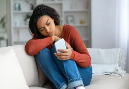 Woman sitting on a couch with her phone in her hands.