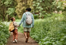 Woman and her child holding hands and walking along a path through a forest