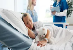 A child lying in bed while parent and doctor talk