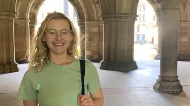 Frances smiling under stone archways at historic university building