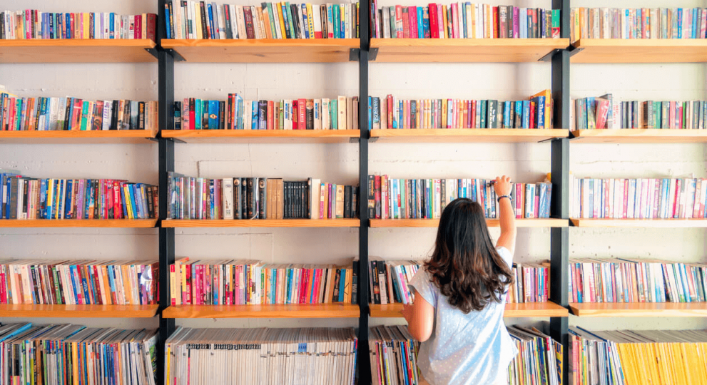 Woman in a library getting books of a bookshelf